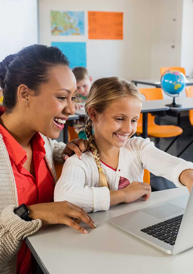 female teacher helping female student at her desk